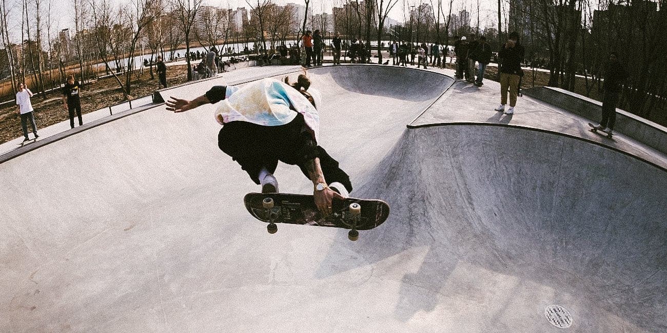 Skateboarder dropping into a concrete bowl at a riverside skatepark