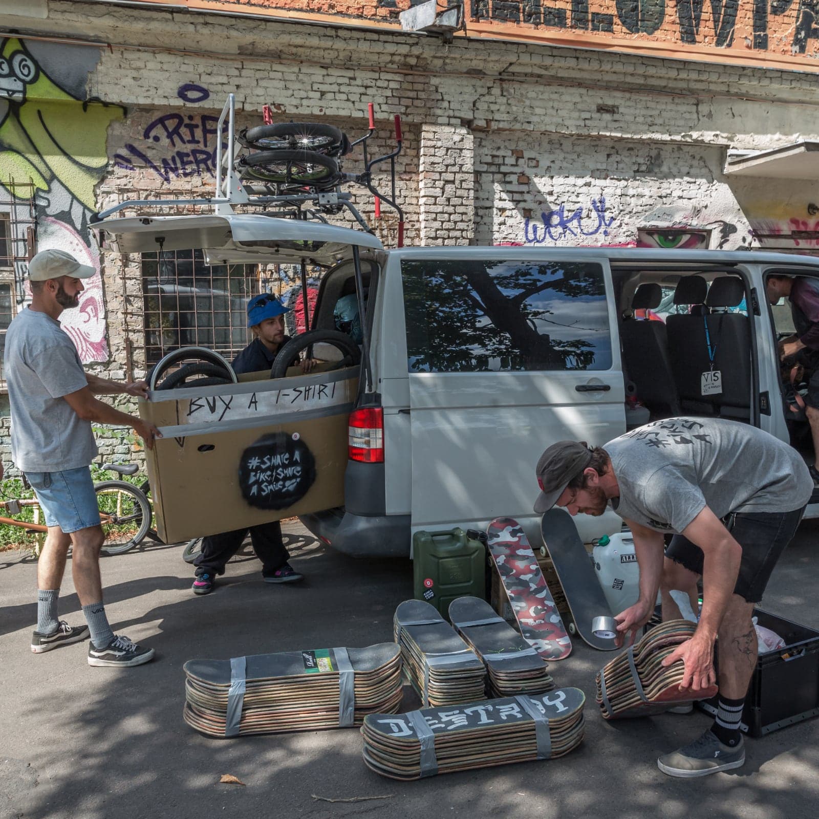 Volunteers loading taped bundles of skateboard decks and bikes into the convoy van