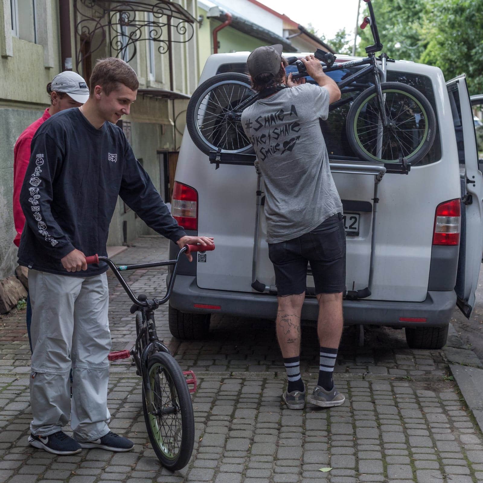 Handing a BMX down from the van's rack to a young rider in Ukraine