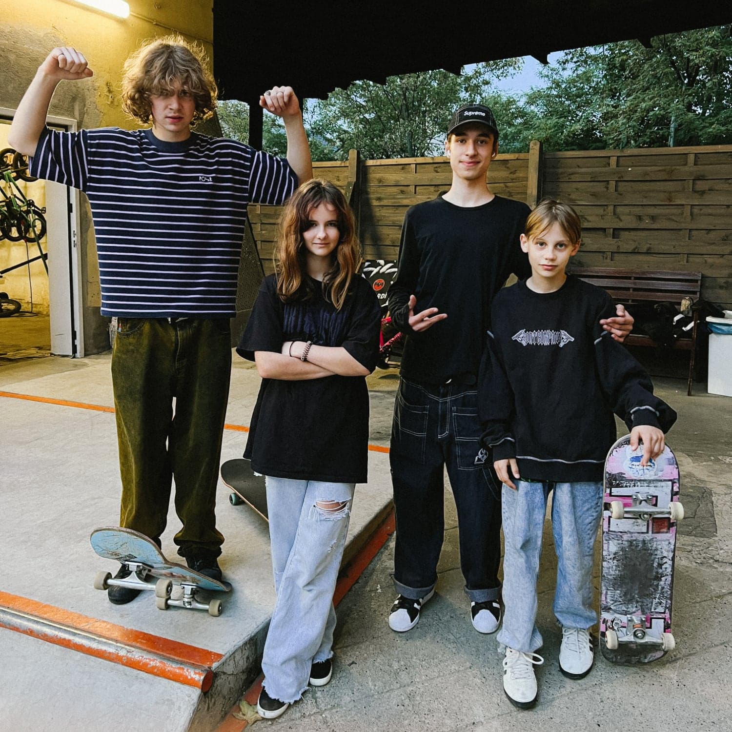 Four teenage students standing with their skateboards after a group lesson